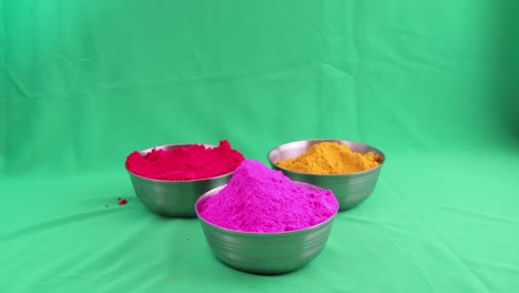 colorful holi | unidentified human hand setting bowls of coloured powder on a green screen | holi stock video for commercials and advertisement|