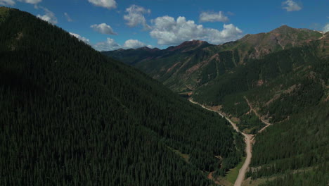 Filmische-Luftdrohne-Im-Sommer,-Unbefestigte-Straße-In-Großer-Höhe,-Skigebiet-Silverton-Mountain-Im-Süden-Colorados,-Blauer-Himmel-Am-Späten-Morgen,-Atemberaubender-üppiger-Grüner-Blauer-Himmel,-Teilweise-Bewölkt,-Felsige-Berge,-Vorwärtsbewegung