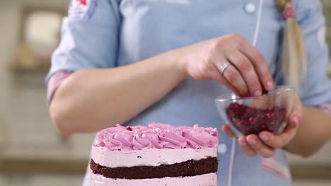 woman decorating a pink layer cake with pomegranate seeds