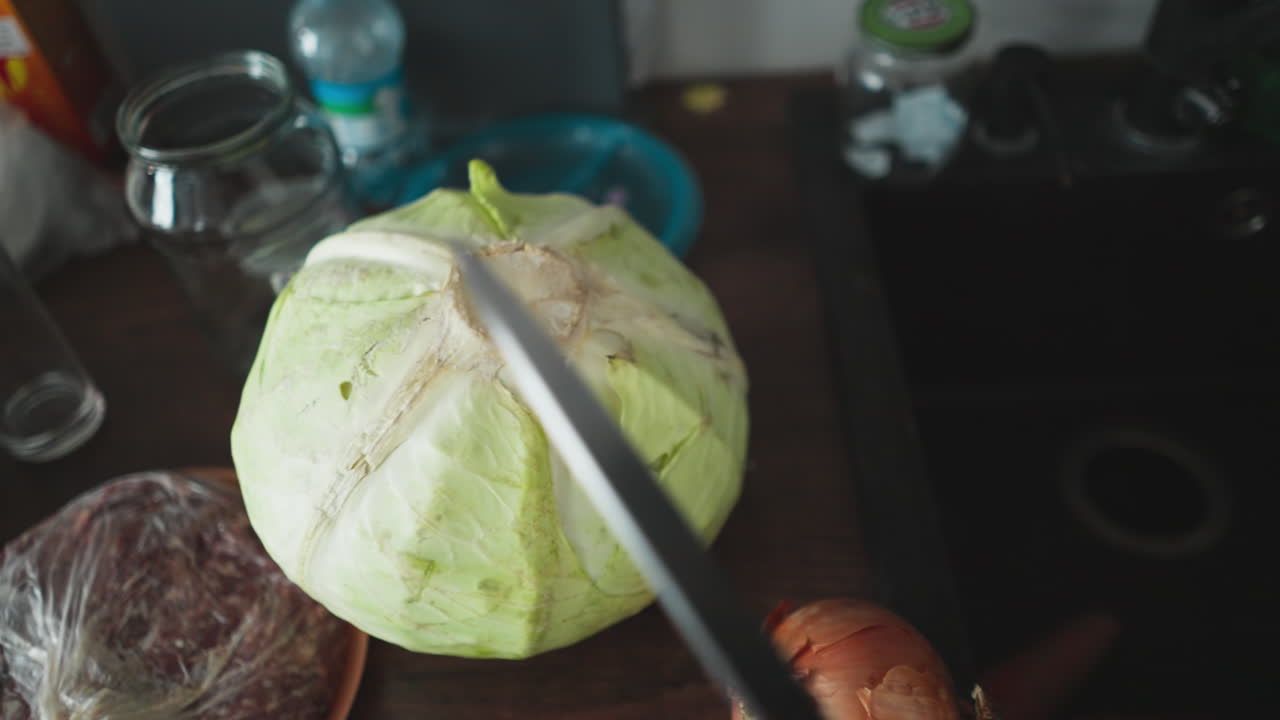 POV of a person inspecting fresh cabbage on kitchen counter with ingredients and knife