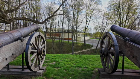 cast iron cannon in wooden recreation support beams with wheels for recoil displayed on hilside under trees