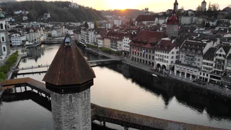 Vista-Aérea-De-Lucerna,-Suiza-Al-Atardecer-Mientras-Cruza-El-Puente-Kappelbrücke-Hacia-Altstadt