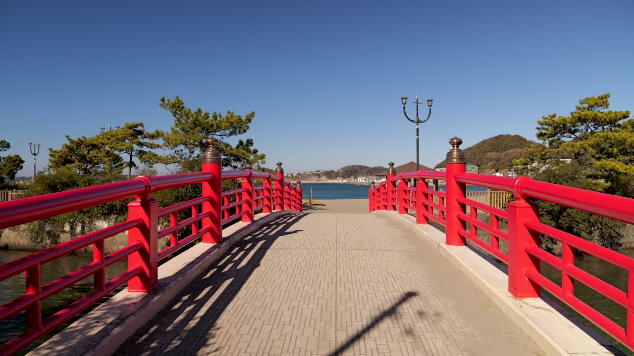 típico puente de madera japonés rojo que conduce al océano en un día soleado de cielo azul
