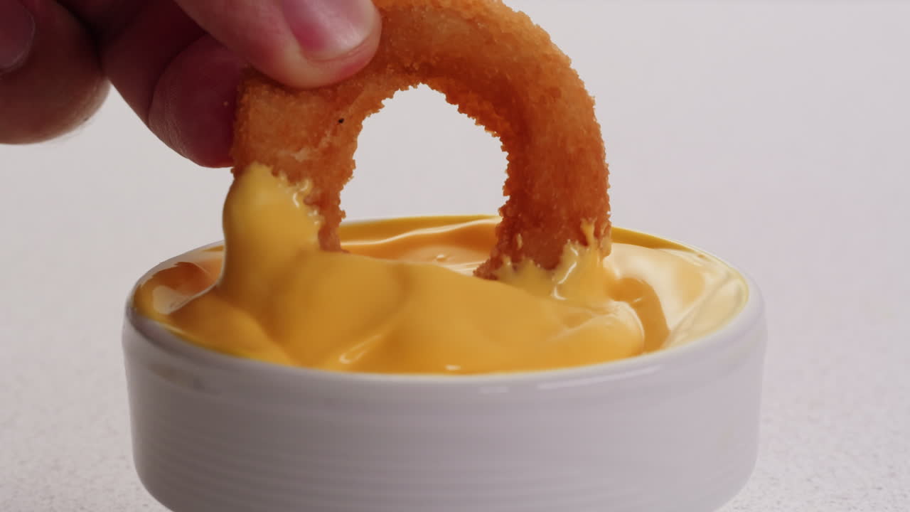Dipping Onion Rings in Cheese Sauce