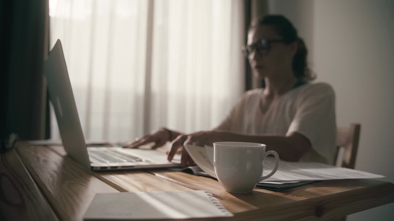 Woman with a stack of papers in her hands sits down at the table
