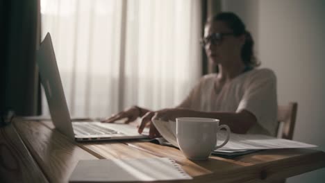 woman with a stack of papers in her hands sits down at the table