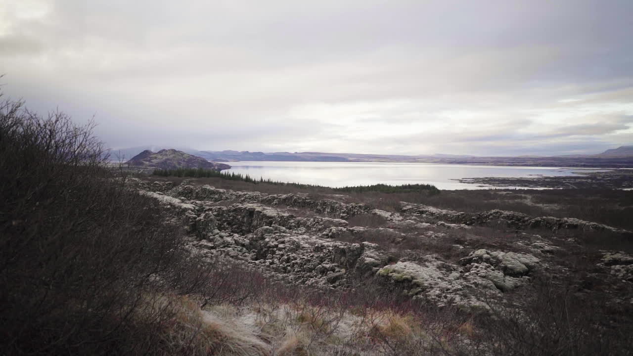 un lento empujón hacia el agua a través de un camino rocoso en reykjavik, islandia con montañas en el fondo