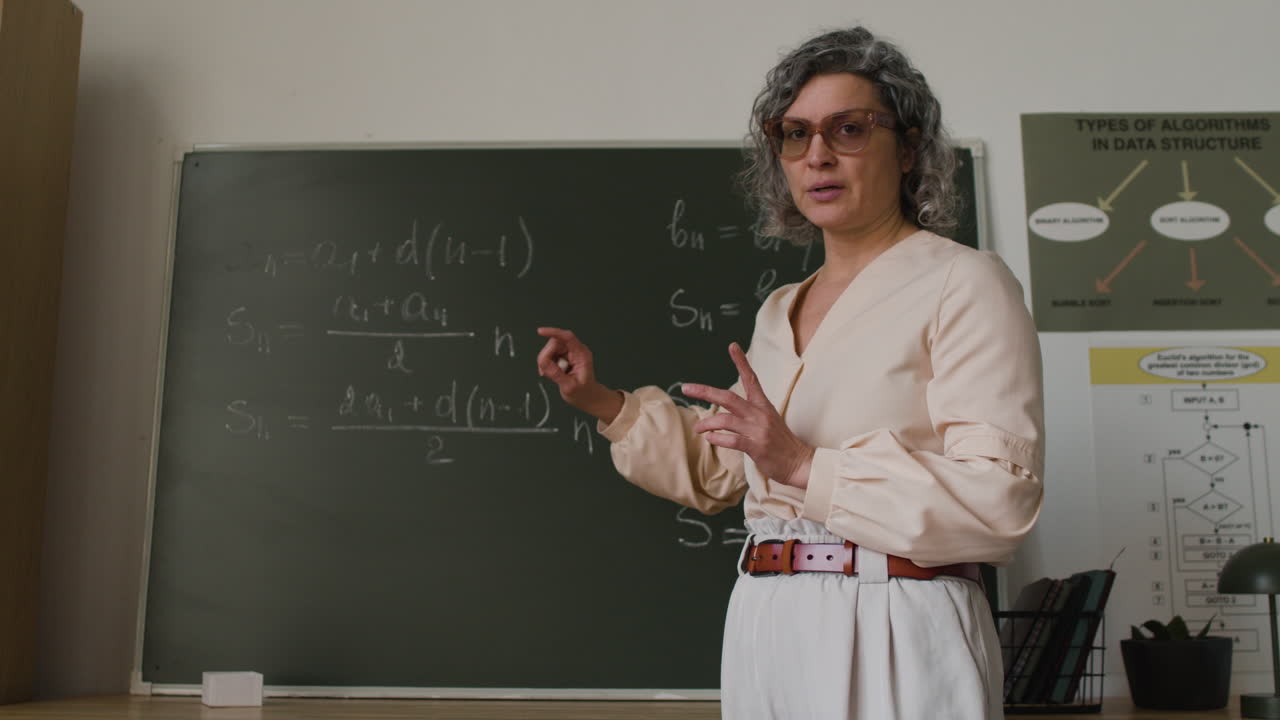 Teacher explaining mathematical formulas on a blackboard