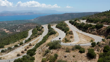 car going down on a winding road by the mountain on a sunny summer day in peloponnese, greece