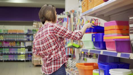 A-young-woman-in-check-shirt-is-choosing-plastic-box-in-the-shopping-center.-4k