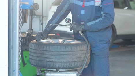 filling the wheel with air from the compressor at the service station. service station, close-up man checking tire pressure, car repair and tyre inflation. professional tire fitting at car service