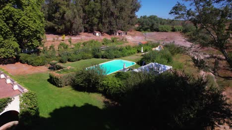 blue in ground pool sits in manicured lawn garden area behind classic portuguese estate home