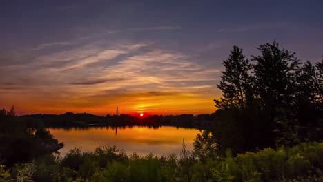 vibrant sunset with reflections and sunbeams over dam in woods