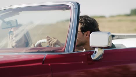 handheld video of happy couple in a red old car