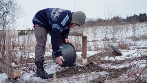 un hombre está extendiendo grava debajo del soporte del marco de una bañera de agua caliente diy - disparo estático