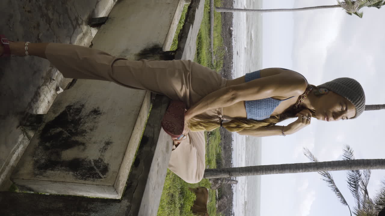 disparo vertical de cardán de una mujer sentada en la pared de una casa abandonada cerca de la playa