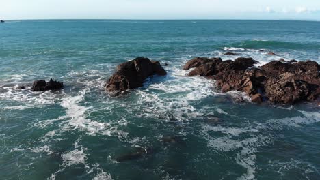 Toma-Aérea-De-Rocas-Golpeadas-Por-Grandes-Olas-En-Un-Día-Soleado