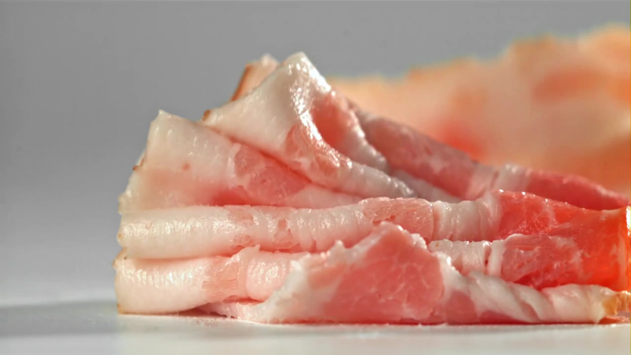 Fette di maiale crudo che cadono e si impilano al rallentatore