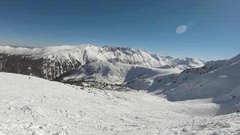 Horizon-of-mountains-covered-with-snow-with-ski-tracks-on-it-and-ski-lift-on-the-side