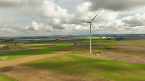 Wind-Turbine-Spinning-Against-Green-Fields-And-Blue-Sky