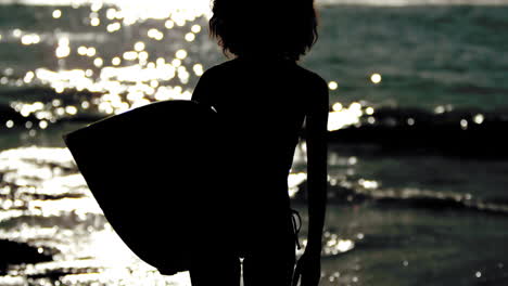 silhouette of an attractive woman holding her surfboard