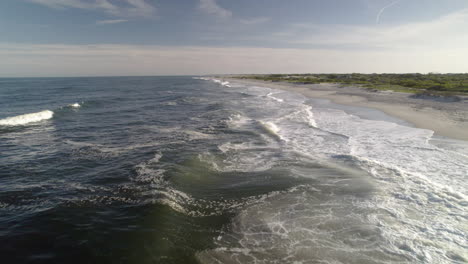 fast drone shot moving down surf of beach over waves, very near water close up