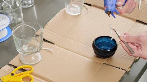 Using-hot-glue-to-place-a-candle-wick-in-containers-for-homemade-crafting