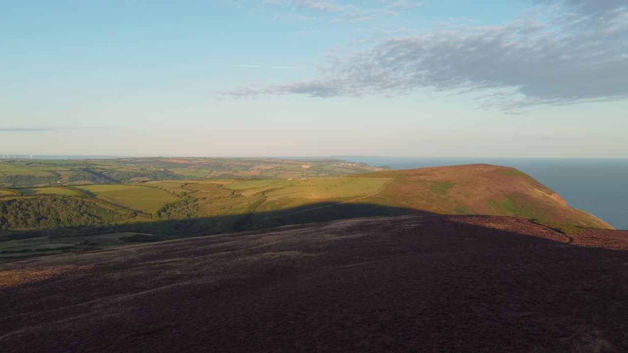 4k 상승하는 공중 드론에서 먼 런디 섬과 작은 마을을 보여주는 일출 해안 농장 풍경