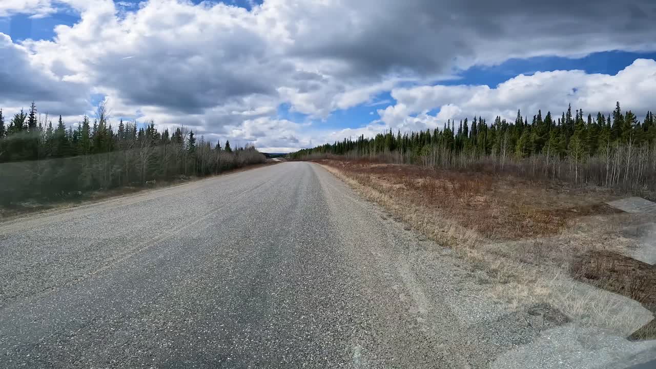 POV - Slowly driving on Highway 1 through a taiga forest in western Yukon Territory on in the early spring; concepts Alaska Highway, travel, wilderness and adventure