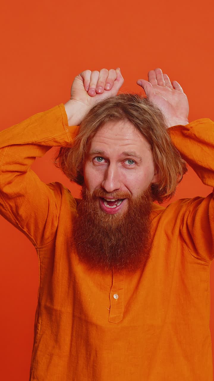Funny man smiling friendly and doing bunny ears gesture having fun fooling easter holidays