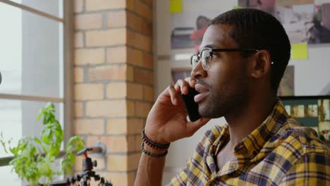 male graphic designer talking on mobile phone at desk in office 4k