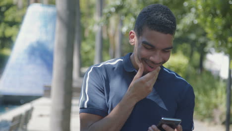 Man-texting-on-phone-outside,-receiving-good-news,-saluting