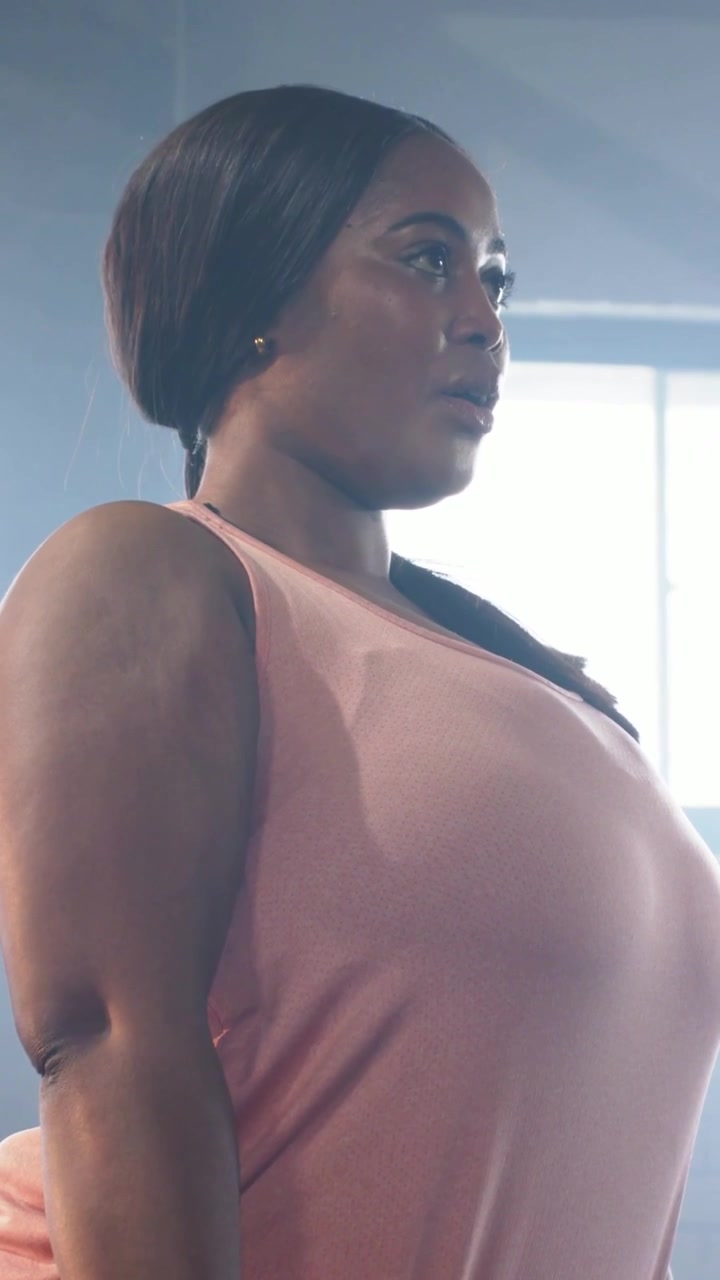 Video verticale: Donna con un top rosa afferra un bilanciere, spinge i fianchi e lo solleva in palestra per la forza