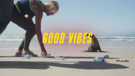 Animation-of-text-good-vibes,-in-yellow,-with-women-picking-up-rubbish-on-beach-with-seal