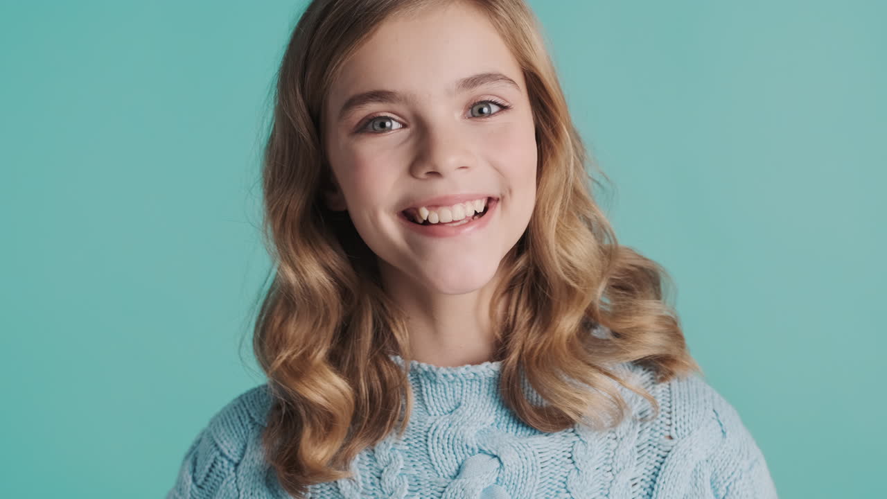 подростковая белая девушка с поднятыми пальцами смотрит в камеру.