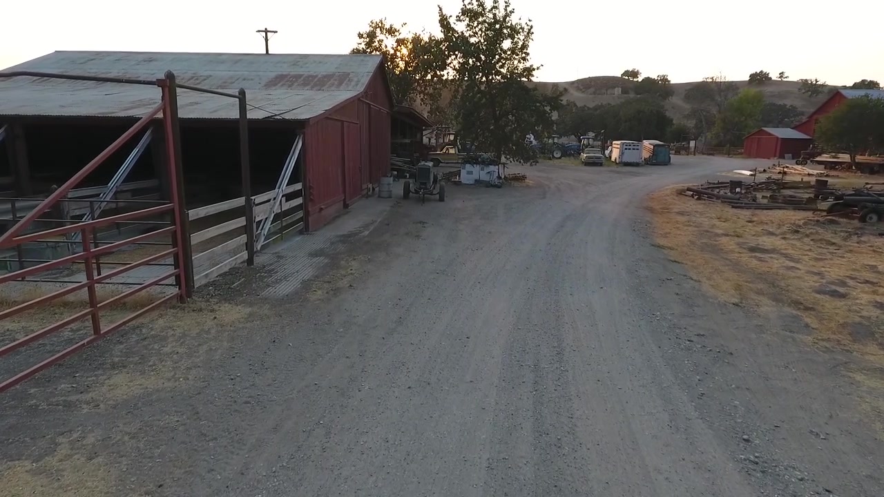 Dron sobrevolando la sede del rancho rodeado de equipo antiguo, graneros y corrales.