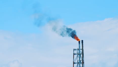 slow motion shot of a large industrial refinery emitting black, polluting smog into a clear blue sky in curacao