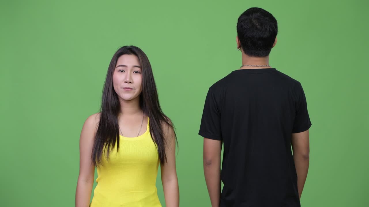 Young Asian woman with young Asian man looking at the back