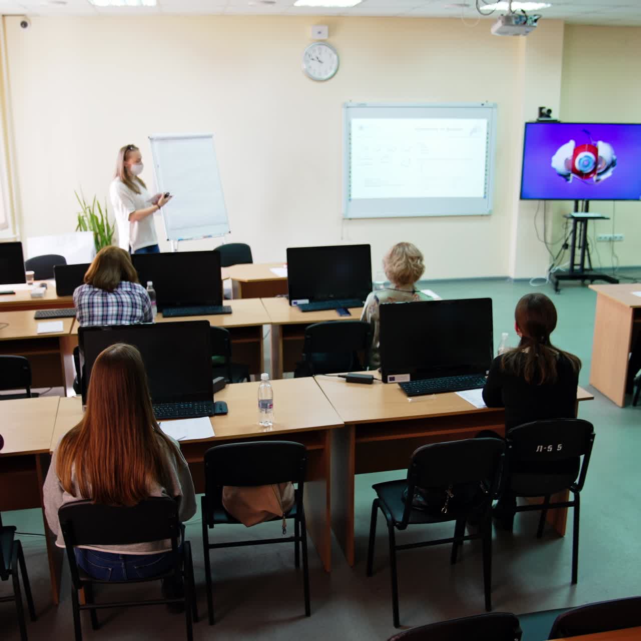 Medical university auditorium with lecture on ophthalmology in process. Students listen to a lecture and look at the screen with eyeball structure