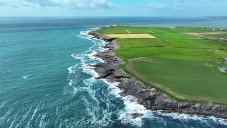 ireland epic locations drone flying over the wave battered coastline of hook head wexford to hook lighthouse on a bright summer morning