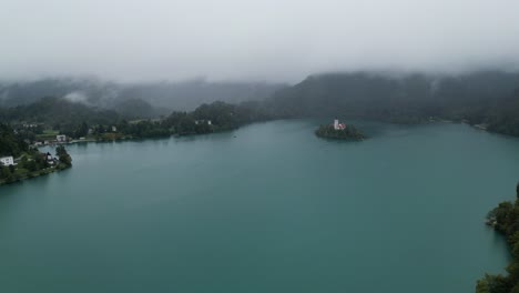 lago bled eslovenia drone vista aérea montañas brumosas en segundo plano