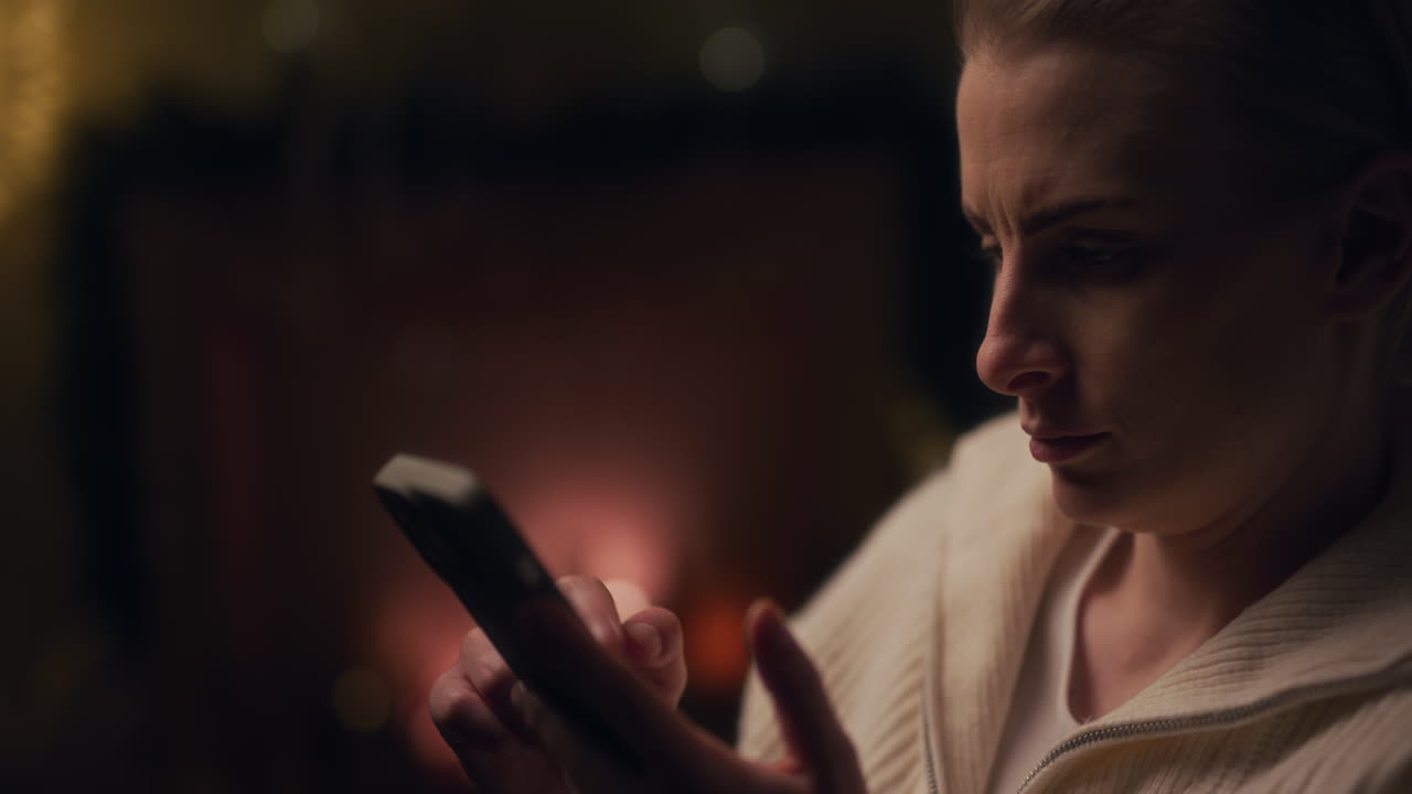 mujer navega por internet con su teléfono inteligente en las redes sociales por la noche contra el fondo de una chimenea en llamas