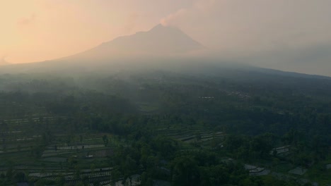 el volcán merapi humeante en una mañana de niebla, vista aérea lejana