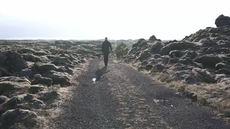 Traveler-walking-along-road-in-rocky-terrain