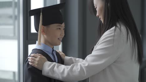 asian mother touching her son, who is graduating.