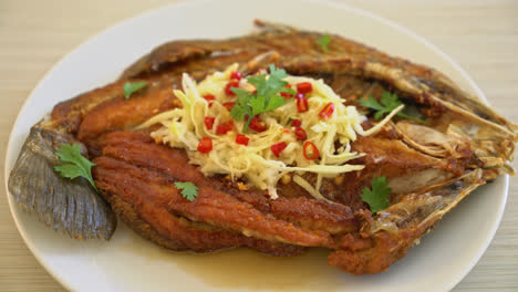 fried sea bass fish with fish sauce and spicy salad on plate