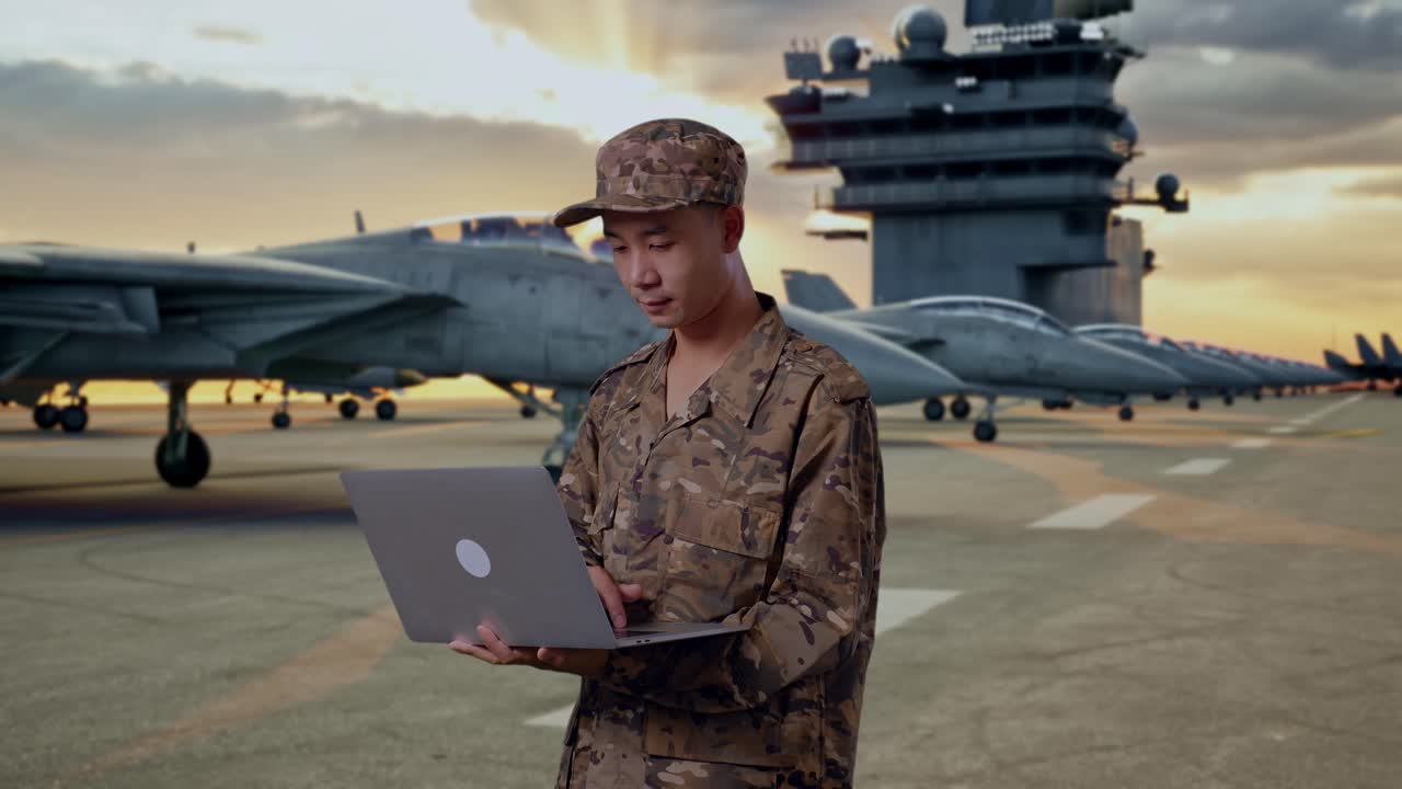 Military Personnel Working on Laptop on Aircraft Carrier Deck at Sunset