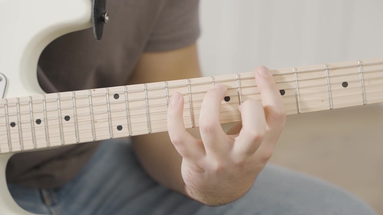 Primo piano di una mano che suona accordi rock ritmici su una chitarra elettrica