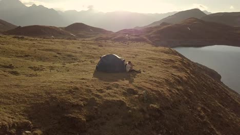 drone dando vueltas alrededor de dos campistas en montañas alpinas al atardecer 4k