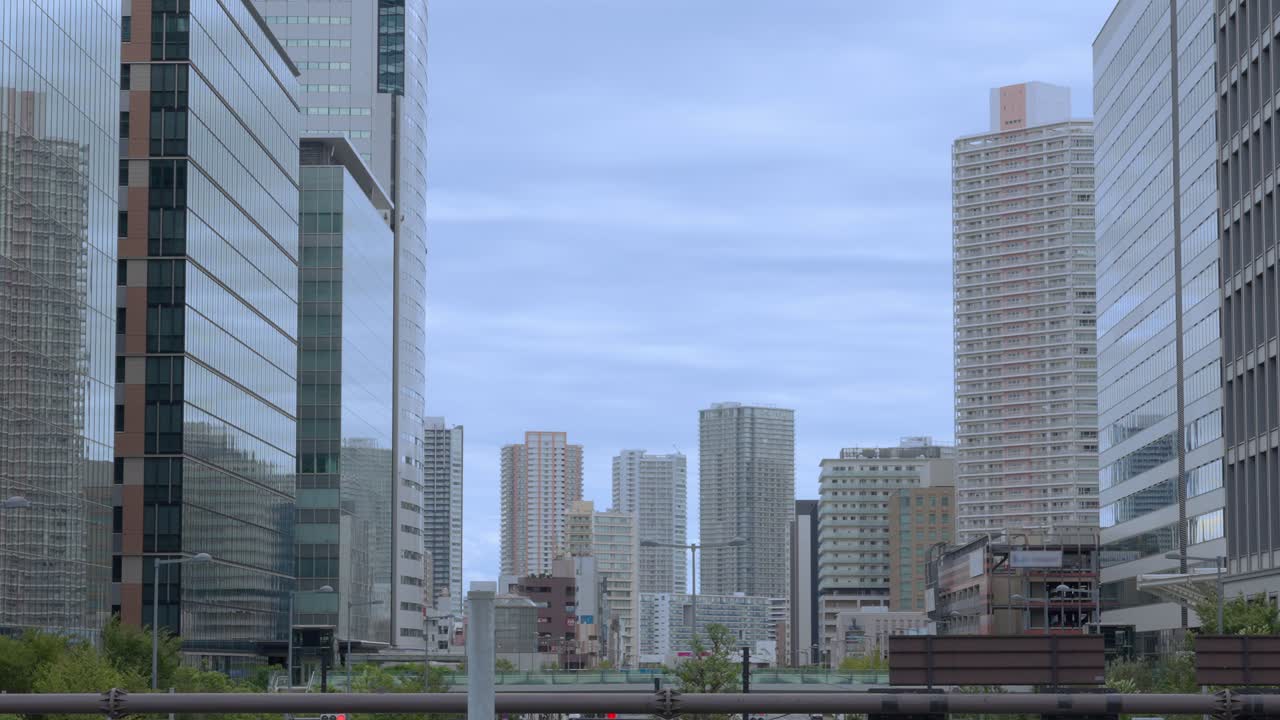 A wide shot of Tokyo's modern high-rise buildings in the Toyosu area against an overcast sky